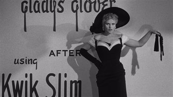 Movie still from “It Should Happen to You” (1954), directed by George Cukor – A black and white photo of a woman in a dress and hat; Medium shot, Low angle