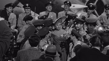 Movie still from “It Should Happen to You” (1954), directed by George Cukor – A group of people in uniform gathered around a woman in a hat; Wide shot, High angle