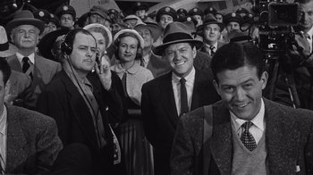Movie still from “It Should Happen to You” (1954), directed by George Cukor – A group of men and women wearing hats and suits; Medium shot, Low angle