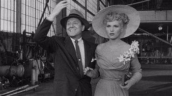 Movie still from “It Should Happen to You” (1954), directed by George Cukor – A man and a woman standing next to each other in front of a building; Medium shot, Low angle