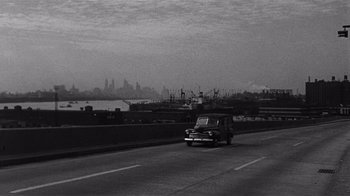 Movie still from “It Should Happen to You” (1954), directed by George Cukor – A black and white photo of a car on the road; Extreme Wide shot, High angle