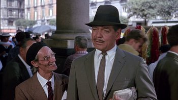 Movie still from “It Started in Naples” (1960), directed by Melville Shavelson – A man in a suit and a hat standing next to another man in a suit; Medium shot, Over the shoulder angle