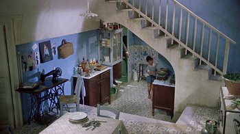 Movie still from “It Started in Naples” (1960), directed by Melville Shavelson – A woman in a kitchen with a sink and a stove; Wide shot, High angle