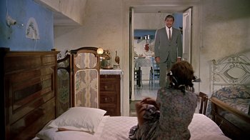 Movie still from “It Started in Naples” (1960), directed by Melville Shavelson – A woman sitting on a bed taking a picture of a man in a suit; Wide shot, Over the shoulder angle