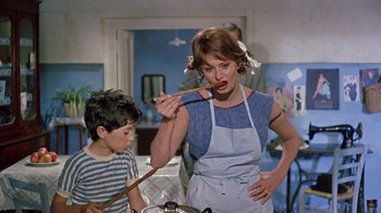 Movie still from “It Started in Naples” (1960), directed by Melville Shavelson – A woman and a boy are cooking in a kitchen; Medium shot, Low angle