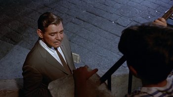 Movie still from “It Started in Naples” (1960), directed by Melville Shavelson – A man in a brown suit is being interviewed by a camera; Medium shot, High angle