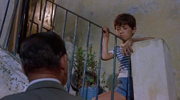 Movie still from “It Started in Naples” (1960), directed by Melville Shavelson – A young boy standing next to an older man on stairs; Medium shot, Low angle