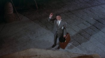 Movie still from “It Started in Naples” (1960), directed by Melville Shavelson – A man holding a briefcase and waving at the camera; Wide shot, High angle
