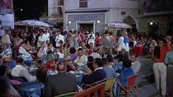Movie still from “It Started in Naples” (1960), directed by Melville Shavelson – A crowd of people sitting at tables outside of a restaurant; Wide shot, High angle