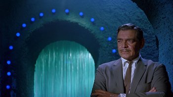 Movie still from “It Started in Naples” (1960), directed by Melville Shavelson – A man in a gray suit standing in front of a waterfall; Medium shot, Over the shoulder angle