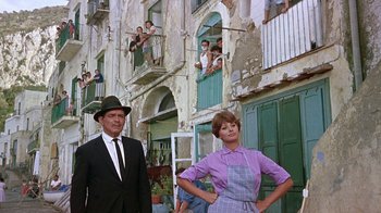Movie still from “It Started in Naples” (1960), directed by Melville Shavelson – A man and a woman standing next to each other in front of a building; Wide shot, Low angle