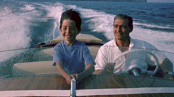 Movie still from “It Started in Naples” (1960), directed by Melville Shavelson – A man and a boy sitting in a boat on the water; Medium shot, High angle