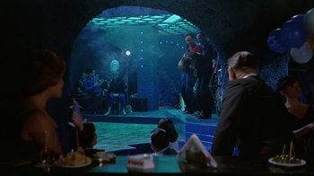 Movie still from “It Started in Naples” (1960), directed by Melville Shavelson – A group of people sitting on a stage in front of an audience; Wide shot, Over the shoulder angle