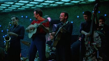 Movie still from “It Started in Naples” (1960), directed by Melville Shavelson – A group of men playing musical instruments on stage; Medium shot, Low angle