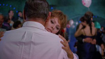 Movie still from “It Started in Naples” (1960), directed by Melville Shavelson – A man and a woman hugging each other in front of a crowd; Medium shot, Over the shoulder angle