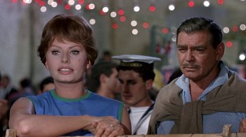 Movie still from “It Started in Naples” (1960), directed by Melville Shavelson – A man and a woman sitting next to each other in front of lights; Medium shot, Over the shoulder angle