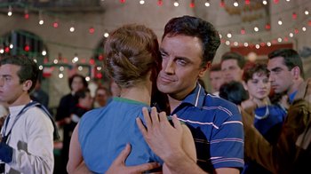 Movie still from “It Started in Naples” (1960), directed by Melville Shavelson – A man and a woman hugging in front of a crowd of onlookers; Medium shot, Low angle