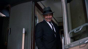 Movie still from “It Started in Naples” (1960), directed by Melville Shavelson – A man in a suit and hat standing in a train; Medium shot, High angle