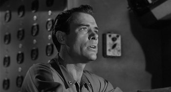 Movie still from “It! The Terror from Beyond Space” (1958), directed by Edward L. Cahn – Black and white photograph of a man looking up; Close Up shot, Low angle