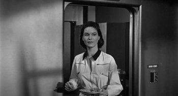 Movie still from “It! The Terror from Beyond Space” (1958), directed by Edward L. Cahn – Black and white photograph of a woman holding a plate of food; Medium shot, Low angle