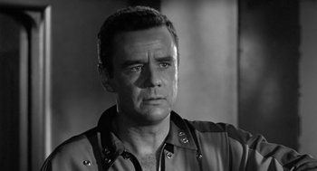 Movie still from “It! The Terror from Beyond Space” (1958), directed by Edward L. Cahn – Black and white photograph of a man in a jacket looking to his left; Close Up shot, Low angle