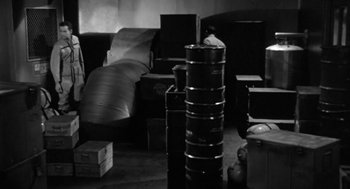 Movie still from “It! The Terror from Beyond Space” (1958), directed by Edward L. Cahn – A black and white photo of a living room with boxes; Wide shot, High angle