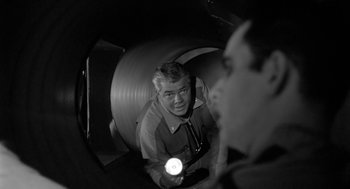 Movie still from “It! The Terror from Beyond Space” (1958), directed by Edward L. Cahn – A man is holding a flashlight in a tunnel; Medium shot, High angle