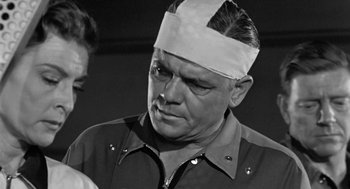 Movie still from “It! The Terror from Beyond Space” (1958), directed by Edward L. Cahn – An old photo of a man with a bandage on his head; Close Up shot, Over the shoulder angle