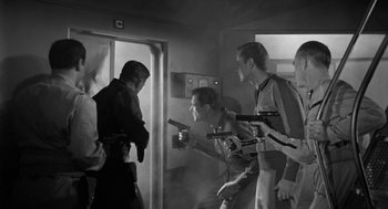 Movie still from “It! The Terror from Beyond Space” (1958), directed by Edward L. Cahn – A black and white photo of a group of men holding guns; Medium shot, Low angle