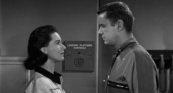 Movie still from “It! The Terror from Beyond Space” (1958), directed by Edward L. Cahn – A man and a woman standing next to each other in front of a building; Medium shot, Low angle