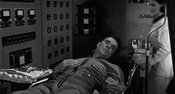 Movie still from “It! The Terror from Beyond Space” (1958), directed by Edward L. Cahn – A black and white photo of a man laying down; Medium shot, High angle