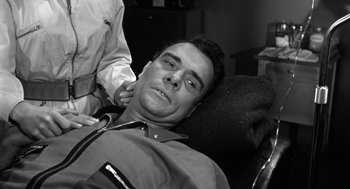 Movie still from “It! The Terror from Beyond Space” (1958), directed by Edward L. Cahn – A black and white photo of a man getting his teeth brushed; Close Up shot, High angle