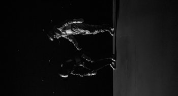 Movie still from “It! The Terror from Beyond Space” (1958), directed by Edward L. Cahn – Two people standing on the side of a building; Wide shot, Low angle