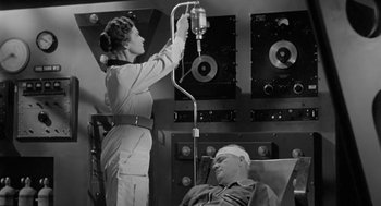 Movie still from “It! The Terror from Beyond Space” (1958), directed by Edward L. Cahn – An old black and white photo of a woman and a man; Medium shot, Low angle