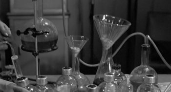 Movie still from “It! The Terror from Beyond Space” (1958), directed by Edward L. Cahn – A black and white photo of a bunch of glassware on a table; Extreme Close Up shot, High angle