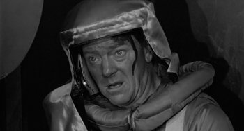 Movie still from “It! The Terror from Beyond Space” (1958), directed by Edward L. Cahn – A black and white photo of a man wearing a helmet; Close Up shot, High angle