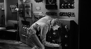 Movie still from “It! The Terror from Beyond Space” (1958), directed by Edward L. Cahn – A man working in an electrical room with many switches; Medium shot, Low angle