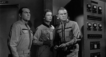 Movie still from “It! The Terror from Beyond Space” (1958), directed by Edward L. Cahn – A black and white photo of three people standing next to each other; Medium shot, Low angle