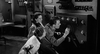 Movie still from “It! The Terror from Beyond Space” (1958), directed by Edward L. Cahn – A man and a woman and a little girl are looking at an oven; Medium shot, Low angle