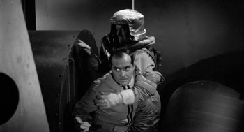 Movie still from “It! The Terror from Beyond Space” (1958), directed by Edward L. Cahn – A black and white photo of a man and a woman; Medium shot, Low angle