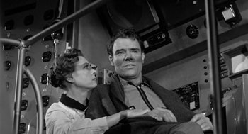 Movie still from “It! The Terror from Beyond Space” (1958), directed by Edward L. Cahn – An older woman sitting next to an older man; Medium shot, Low angle