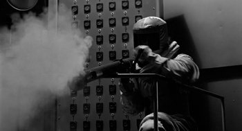 Movie still from “It! The Terror from Beyond Space” (1958), directed by Edward L. Cahn – A person wearing a helmet and holding a gun; Medium shot, Low angle