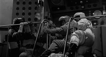 Movie still from “It! The Terror from Beyond Space” (1958), directed by Edward L. Cahn – A black and white photo of people riding a ride; Wide shot, High angle
