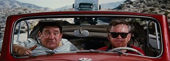 Movie still from “It's a Mad Mad Mad Mad World” (1963), directed by Stanley Kramer – Two men in a red car looking out the window; Medium shot, Low angle