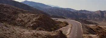 Movie still from “It's a Mad Mad Mad Mad World” (1963), directed by Stanley Kramer – A car driving down a road in the middle of the desert; Extreme Wide shot, High angle