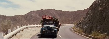Movie still from “It's a Mad Mad Mad Mad World” (1963), directed by Stanley Kramer – An old blue truck with a red cart on the back of it; Wide shot, High angle