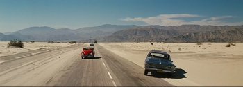 Movie still from “It's a Mad Mad Mad Mad World” (1963), directed by Stanley Kramer – Two cars driving down a road in the middle of the desert; Extreme Wide shot, High angle