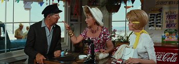 Movie still from “It's a Mad Mad Mad Mad World” (1963), directed by Stanley Kramer – An older woman talking to an older man in a white hat; Medium shot, Over the shoulder angle