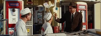 Movie still from “It's a Mad Mad Mad Mad World” (1963), directed by Stanley Kramer – A man in a white hat is eating something; Medium shot, Low angle