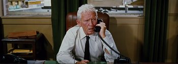 Movie still from “It's a Mad Mad Mad Mad World” (1963), directed by Stanley Kramer – An older man sitting at a desk talking on the phone; Close Up shot, High angle